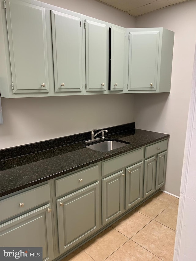 kitchen featuring light tile patterned floors, sink, and dark stone counters