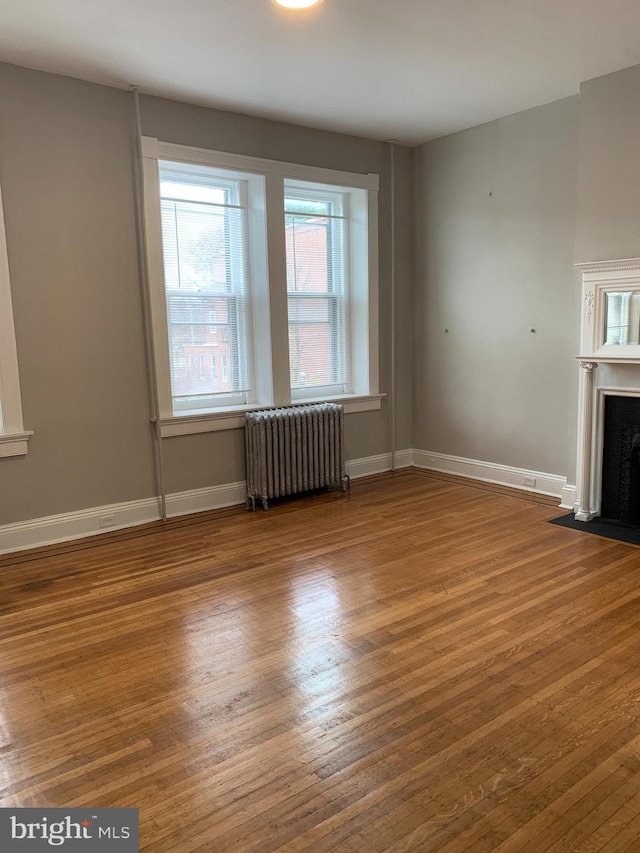 unfurnished living room with wood-type flooring and radiator