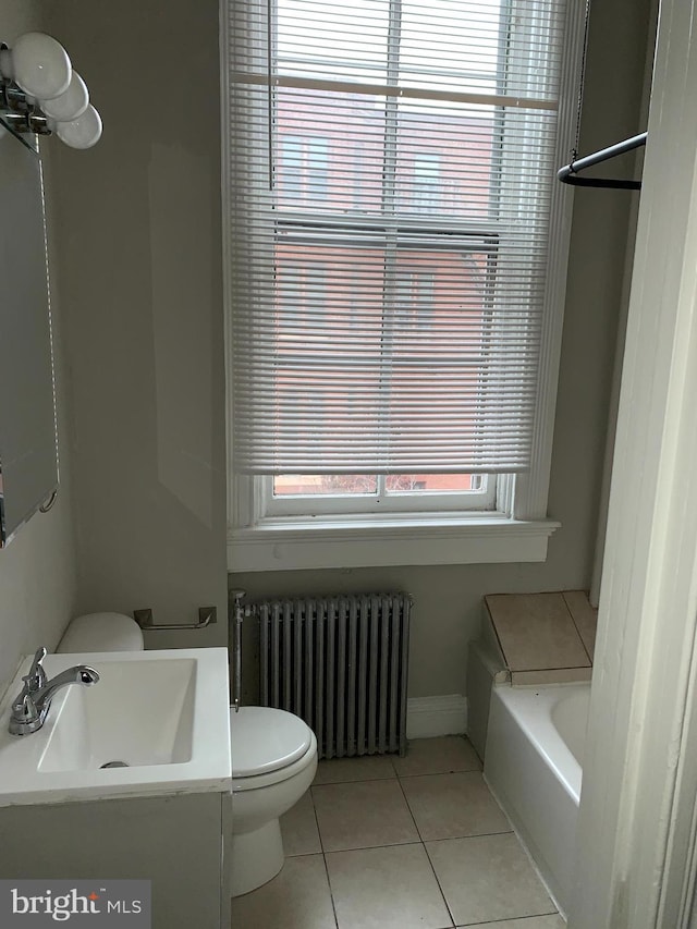 bathroom with radiator, sink, a bath, tile patterned floors, and toilet