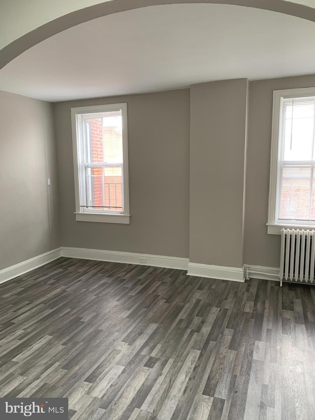 unfurnished room featuring radiator heating unit and dark wood-type flooring