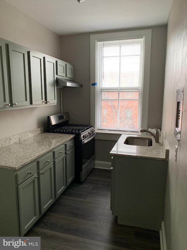 kitchen featuring dark hardwood / wood-style floors, light stone counters, sink, and stainless steel range with gas stovetop