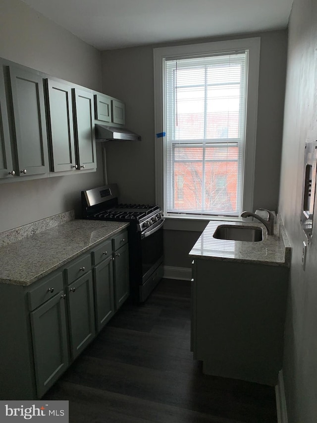 kitchen featuring light stone countertops, gas range, dark hardwood / wood-style flooring, and sink