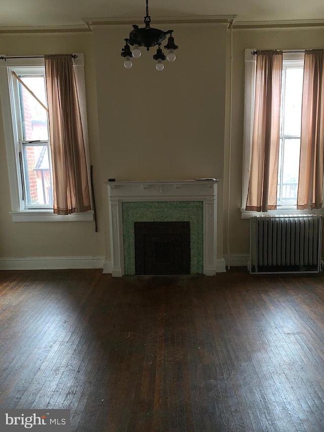 unfurnished living room with dark hardwood / wood-style flooring, radiator, and an inviting chandelier