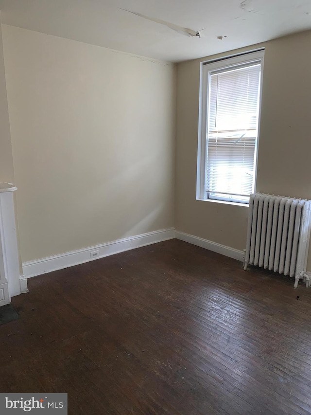 empty room with radiator and dark wood-type flooring