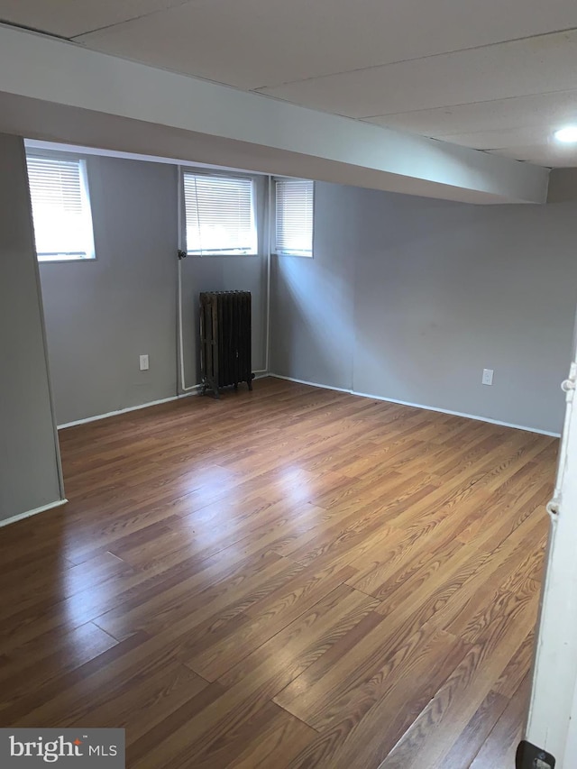 basement with radiator heating unit and hardwood / wood-style flooring