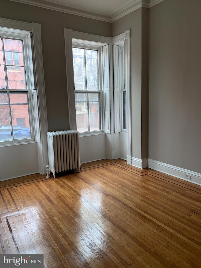 unfurnished room featuring radiator heating unit, light hardwood / wood-style floors, and crown molding