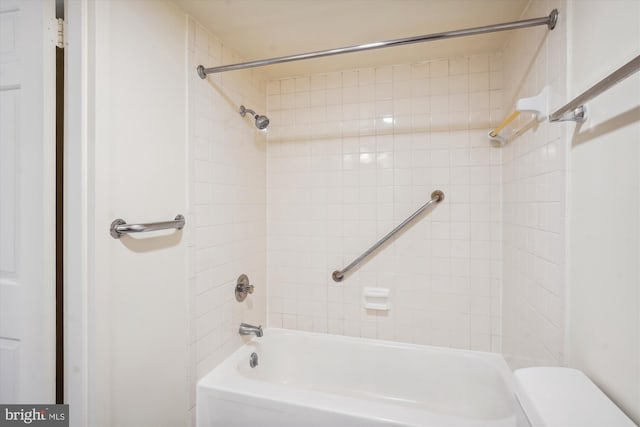 bathroom featuring tiled shower / bath combo and toilet