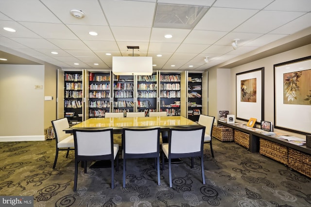 carpeted dining area featuring a paneled ceiling