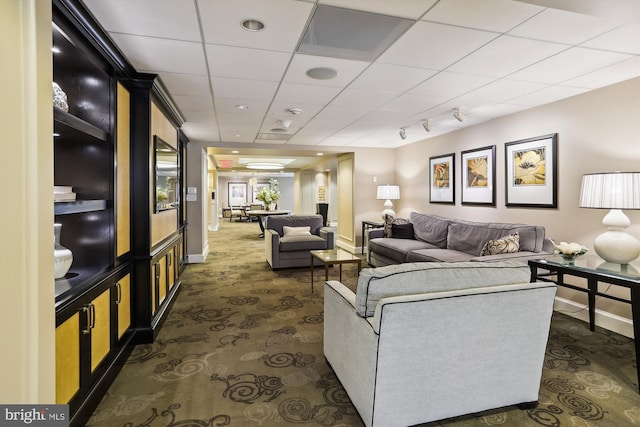 living room featuring dark colored carpet and a drop ceiling