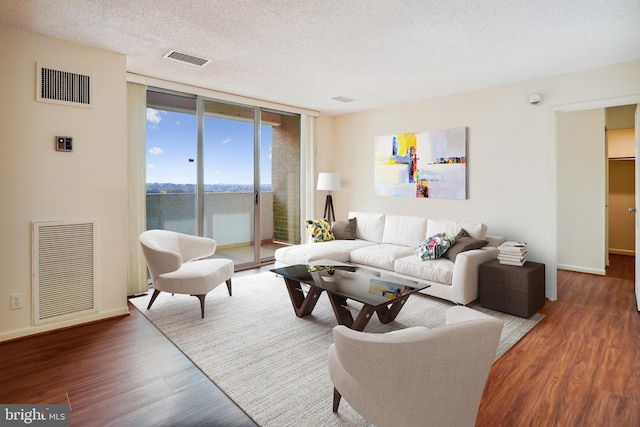 living room with floor to ceiling windows, dark hardwood / wood-style flooring, a water view, and a textured ceiling