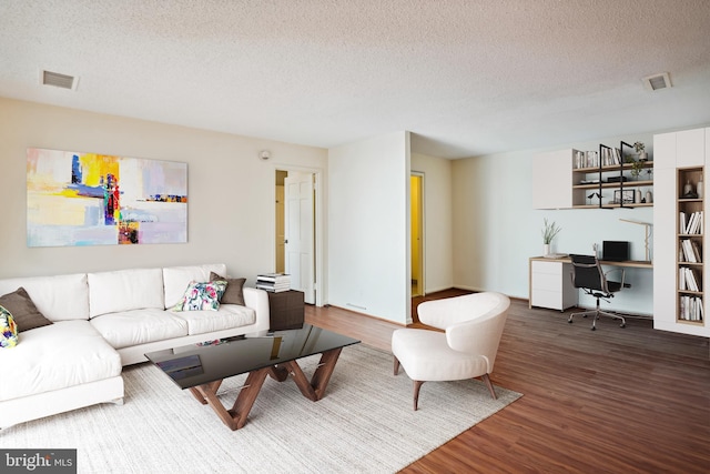 living room featuring dark wood-type flooring and a textured ceiling