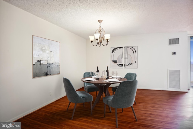 dining room featuring a textured ceiling, dark wood-type flooring, and a notable chandelier