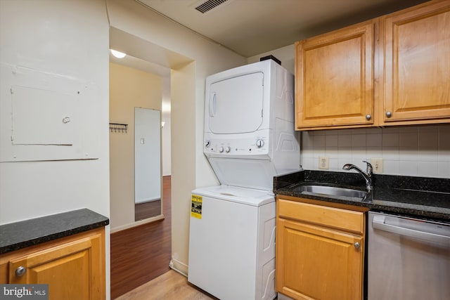 laundry area with sink, stacked washer and dryer, and light hardwood / wood-style flooring