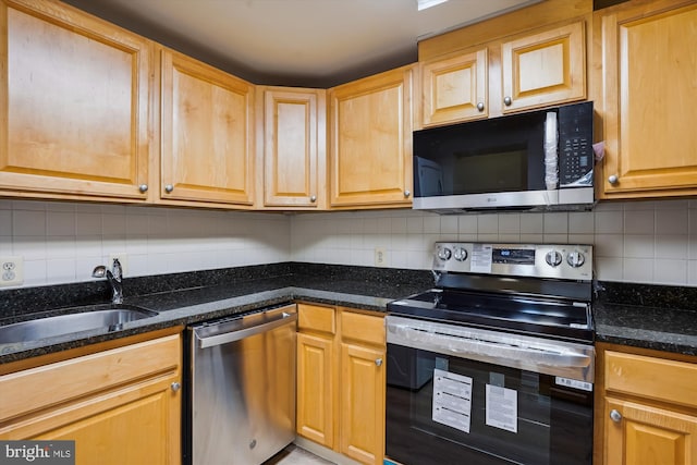 kitchen with dark stone counters, backsplash, sink, and stainless steel appliances