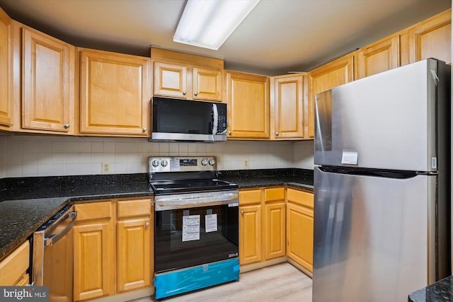 kitchen featuring light wood-type flooring, backsplash, appliances with stainless steel finishes, and dark stone counters