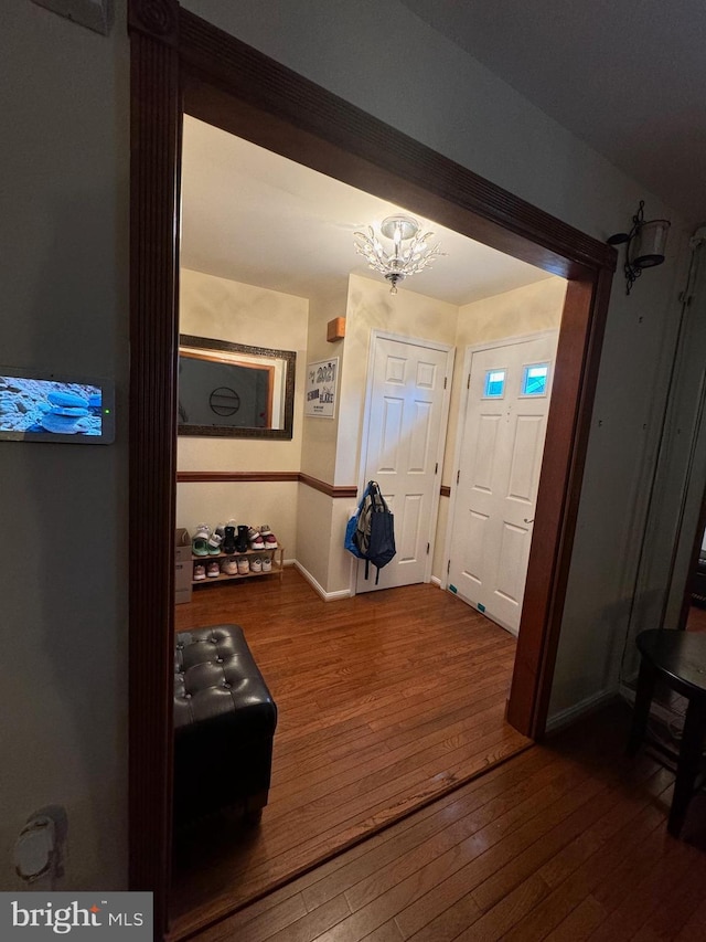 foyer with dark wood-type flooring and a chandelier