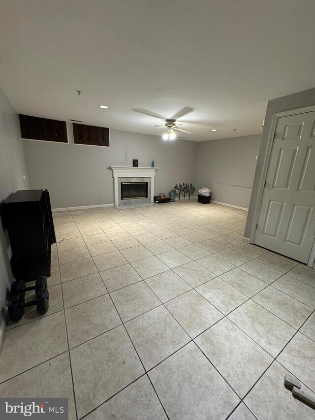 basement featuring ceiling fan and light tile patterned flooring