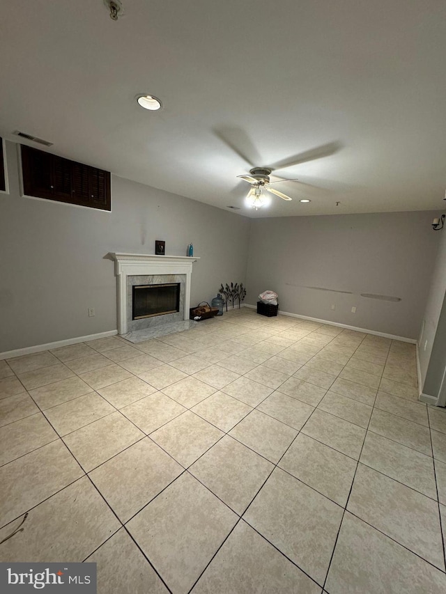 unfurnished living room with a premium fireplace, ceiling fan, and light tile patterned floors