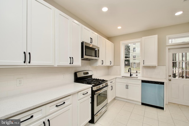 kitchen featuring backsplash, white cabinetry, sink, and appliances with stainless steel finishes