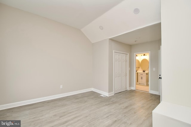 spare room featuring lofted ceiling and light wood-type flooring