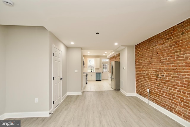 interior space with light hardwood / wood-style flooring and brick wall