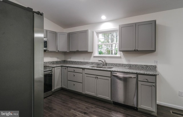 kitchen featuring appliances with stainless steel finishes, dark hardwood / wood-style flooring, gray cabinetry, and sink