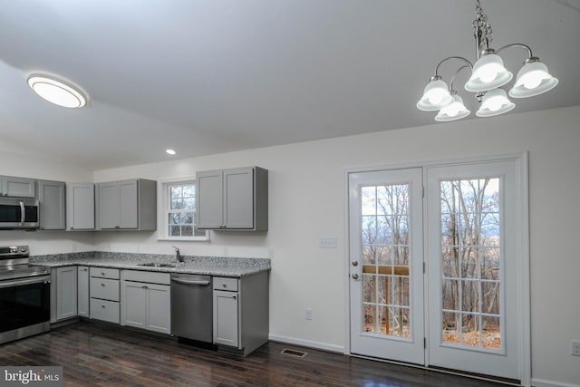 kitchen with appliances with stainless steel finishes, dark hardwood / wood-style floors, hanging light fixtures, and sink