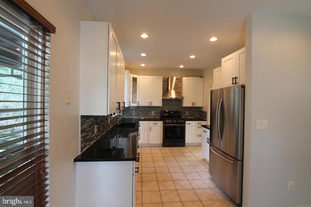 kitchen featuring stainless steel refrigerator, black stove, wall chimney range hood, tasteful backsplash, and white cabinets