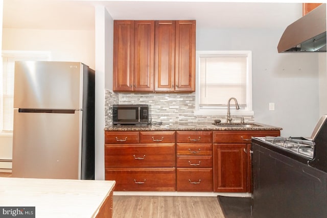 kitchen with sink, stainless steel appliances, baseboard heating, light hardwood / wood-style flooring, and range hood