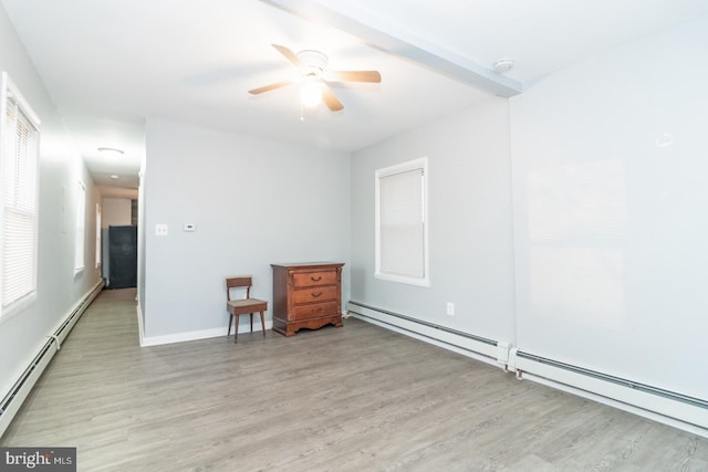 unfurnished room featuring ceiling fan, light wood-type flooring, and a baseboard heating unit