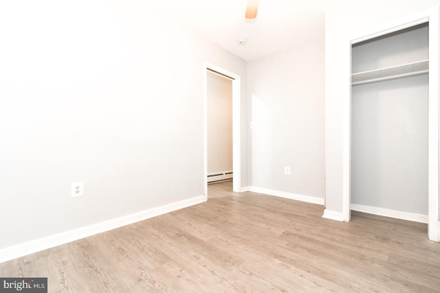 unfurnished bedroom featuring light hardwood / wood-style floors, a baseboard heating unit, and a closet