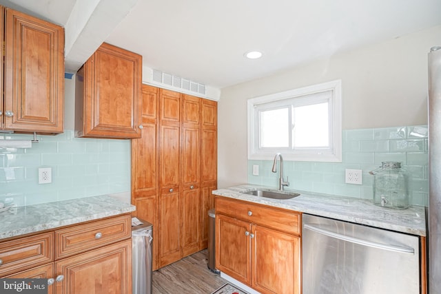 kitchen with light stone countertops, decorative backsplash, light hardwood / wood-style floors, and sink