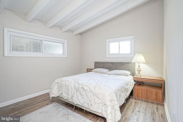 bedroom with vaulted ceiling with beams, light hardwood / wood-style floors, and multiple windows