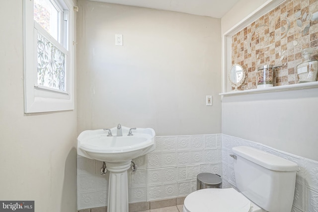 bathroom with toilet and tile walls