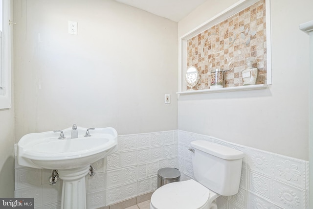 bathroom featuring tile walls and toilet