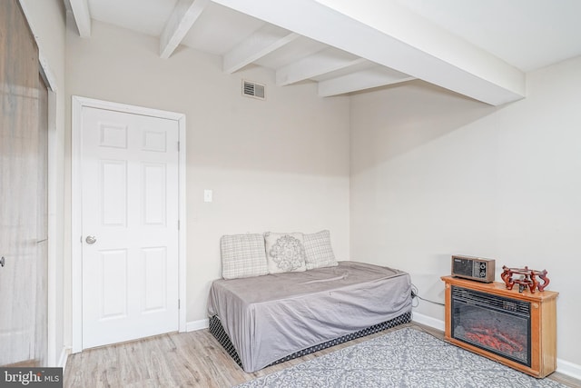 bedroom featuring light hardwood / wood-style flooring and beamed ceiling