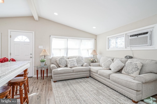 living room featuring lofted ceiling with beams, light hardwood / wood-style flooring, and a wall unit AC