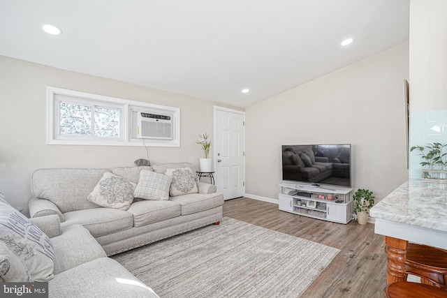 living room with an AC wall unit and light hardwood / wood-style floors