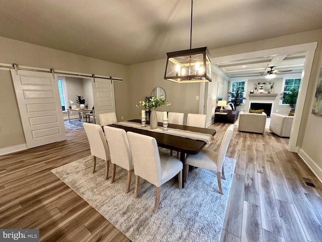 3104 Paper Mill Rd, Phoenix, MD 21131 - dining area featuring a barn door, wood finished floors, a fireplace, baseboards, and a ceiling fan