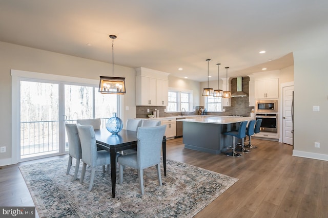 dining area featuring wood-type flooring, sink, and a notable chandelier