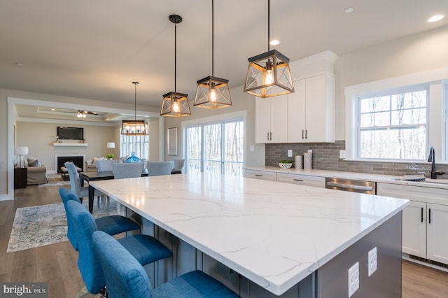 kitchen with hanging light fixtures, white cabinetry, a center island, and sink