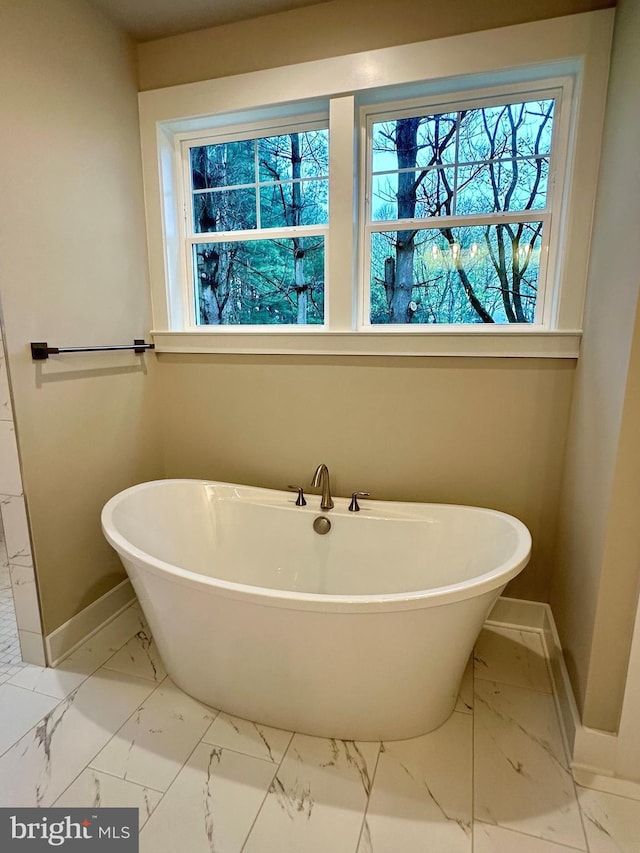 3104 Paper Mill Rd, Phoenix, MD 21131 - bathroom with baseboards, marble look tiles, and a freestanding tub
