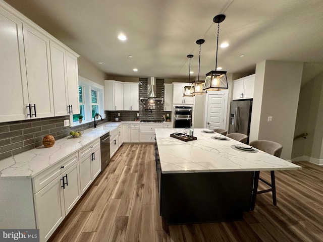 3104 Paper Mill Rd, Phoenix, MD 21131 - kitchen with appliances with stainless steel finishes, wall chimney exhaust hood, a kitchen bar, a center island, and wood finished floors