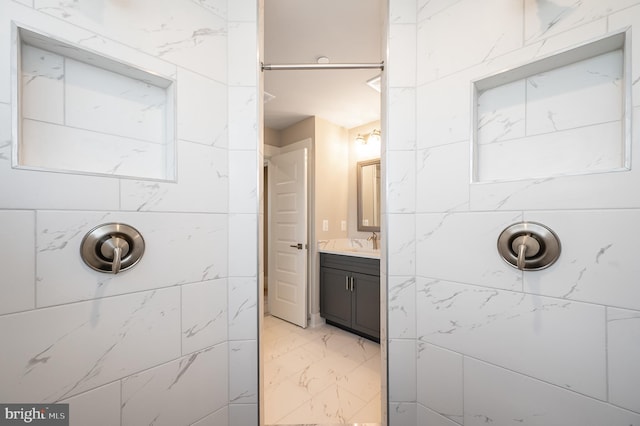 bathroom with tiled shower and vanity