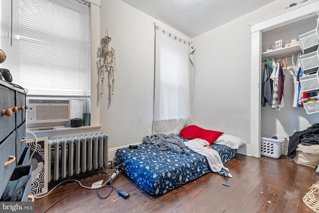 bedroom with hardwood / wood-style floors, radiator, and cooling unit