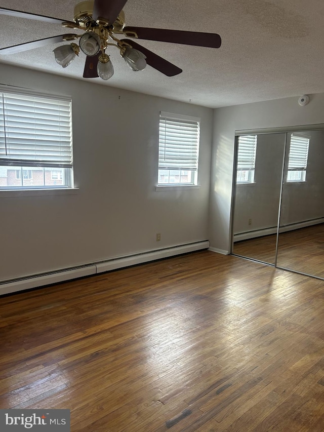 unfurnished bedroom featuring a textured ceiling, multiple windows, ceiling fan, and dark hardwood / wood-style floors