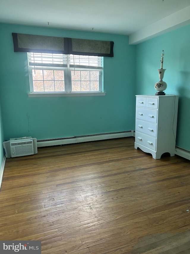 unfurnished bedroom with wood-type flooring and a baseboard heating unit