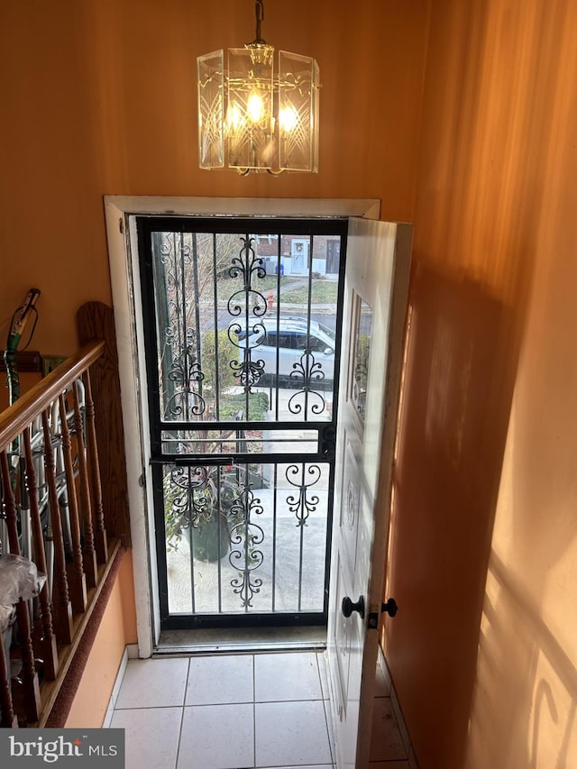 doorway to outside featuring a healthy amount of sunlight, light tile patterned floors, and an inviting chandelier