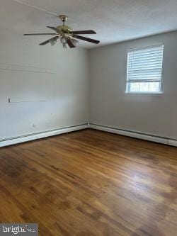 empty room featuring baseboard heating and dark wood-type flooring