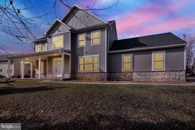 back house at dusk featuring a lawn and a porch